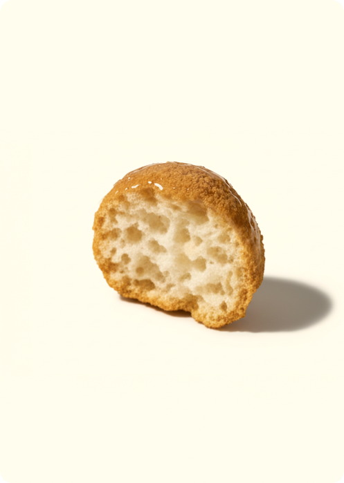 Half of an air-popped lotus seed snack with a golden coating, showing its light, porous interior on a neutral surface.