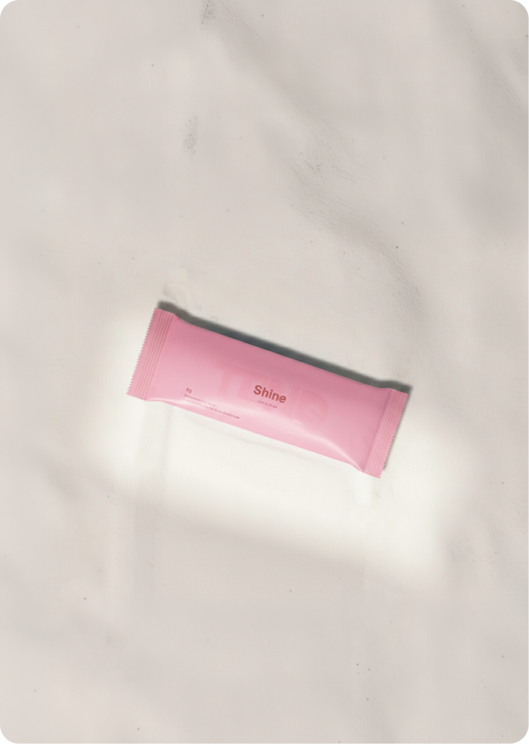 Pink hydration sachet labeled “Shine” on a soft, neutral background.